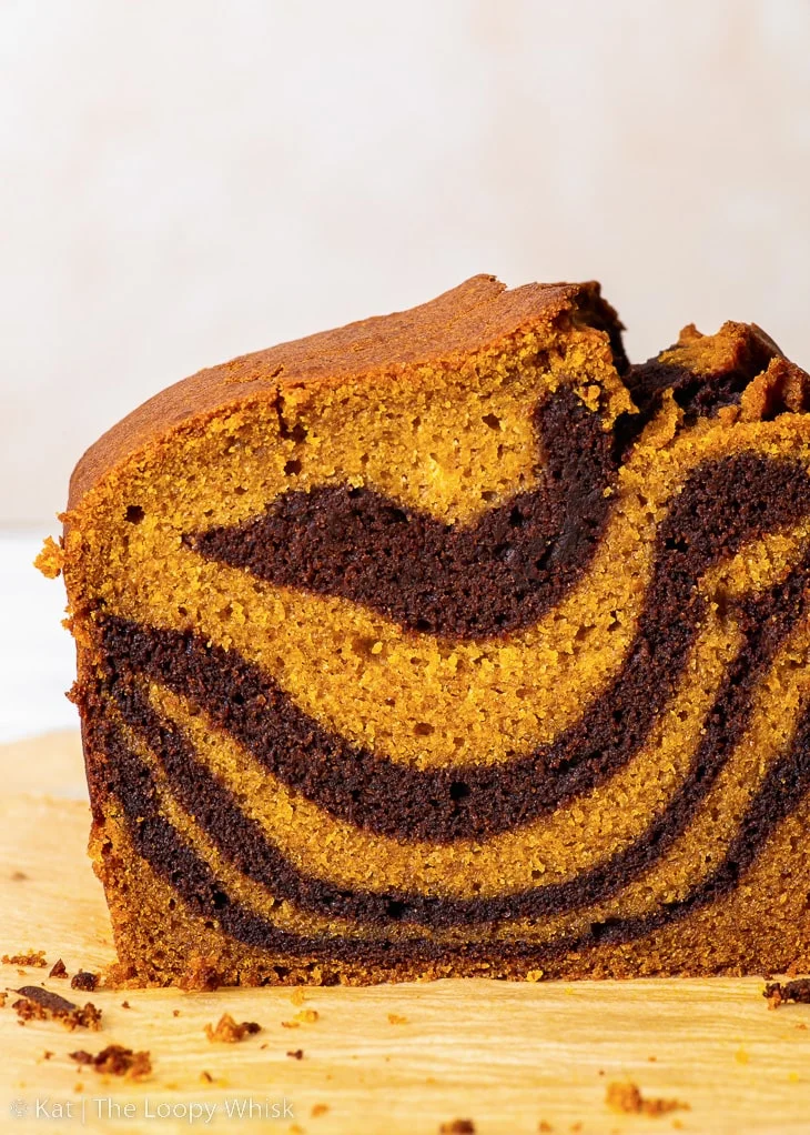 Gâteau marbré à la citrouille sans gluten, avec quelques tranches déjà coupées, sur une feuille de papier sulfurisé brun.