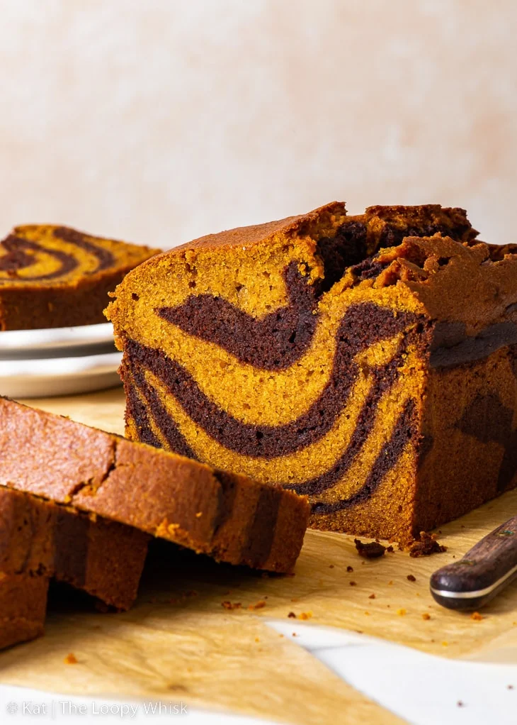 Gâteau marbré à la citrouille sans gluten, avec quelques tranches déjà coupées, sur une feuille de papier sulfurisé brun.